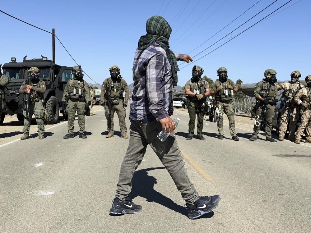 A demonstrator walks in front of federal agents blocking a road during an immigration raid in Camarillo, Calif., Thursday, July 10, 2025.