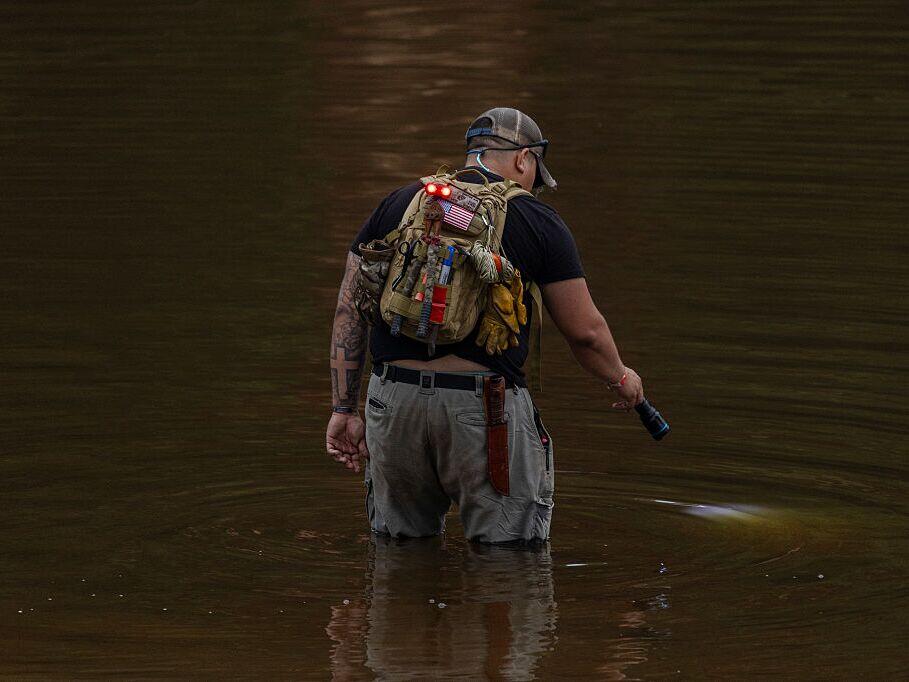 A search and recovery worker shines his flashlight through murky waters on July 6 in Hunt, Texas, two days after deadly flash floods tore through the area.