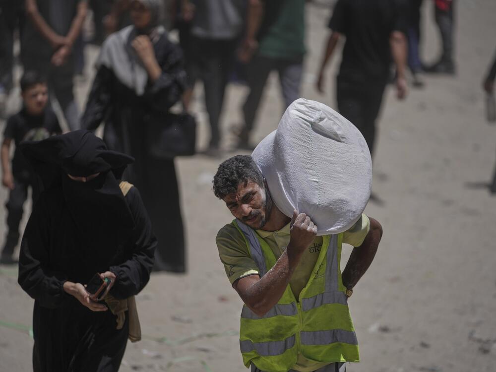 Palestinians carry bags of flour distributed by the World Food Program in Gaza City, northern Gaza Strip, Saturday, July 12, 2025.