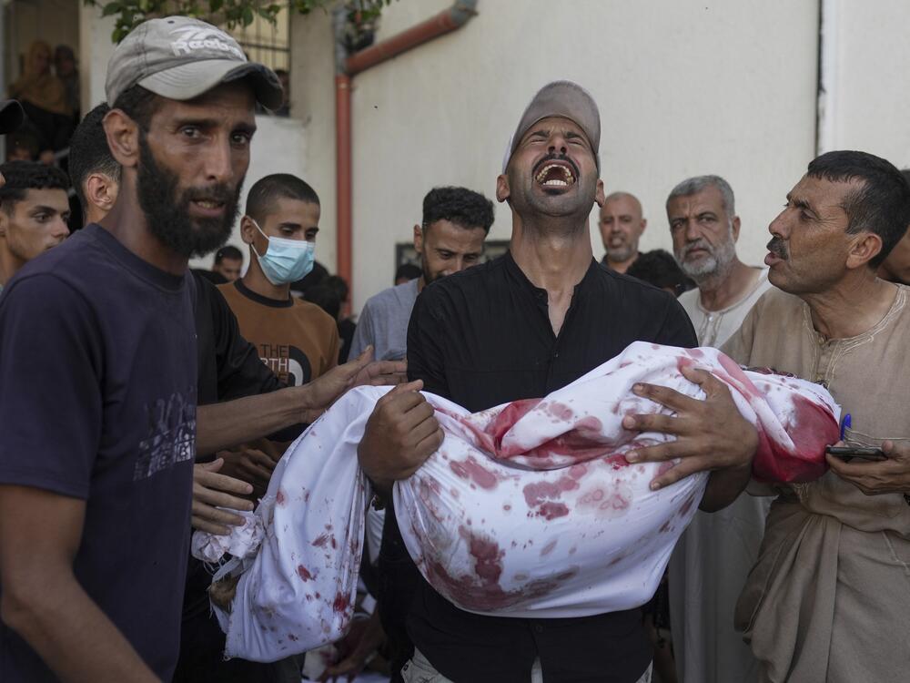 A Palestinian man carries the body of his child, who was killed in an Israeli military airstrike on Gaza, at Shifa Hospital in Gaza City, Saturday, July 12, 2025.
