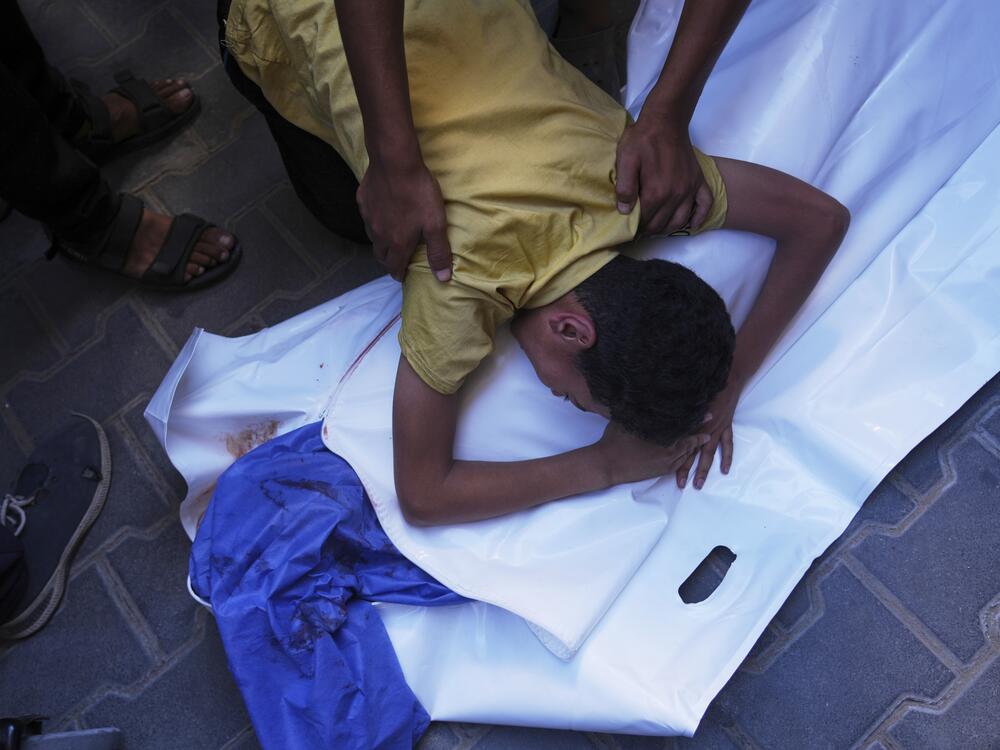 A Palestinian boy mourns over the body of his 12-year-old friend, Abdullah Ahmed, who was killed in an Israeli strike that targeted a drinking water distribution point, at Al-Awda Hospital in Nuseirat, central Gaza Strip, Sunday, July 13, 2025.
