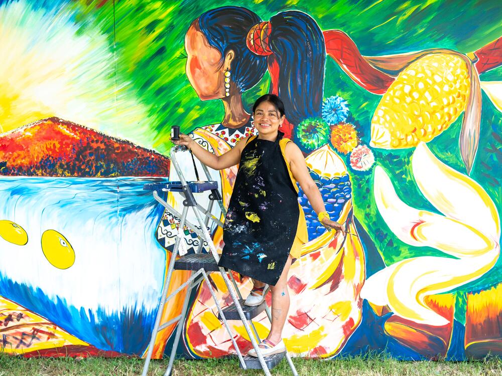 Evelyn del Rosario Morán Cojoc, an artist from Guatemala, creates a mural that depicts traditional foods from her Mayan culture — like that floating ear of corn and three yellow beans. She teaches art to kids across the country, encouraging them to depict their indigenous traditions.