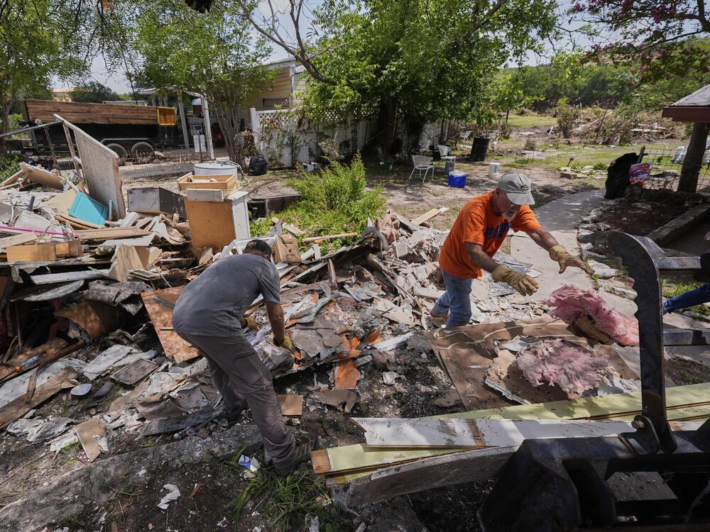 Homeowner Daniel Olivas, right, clears debris from his home that was heavily damaged from flash floods along the Guadalupe River in Kerrville, Texas, on Thursday, July 10, 2025.