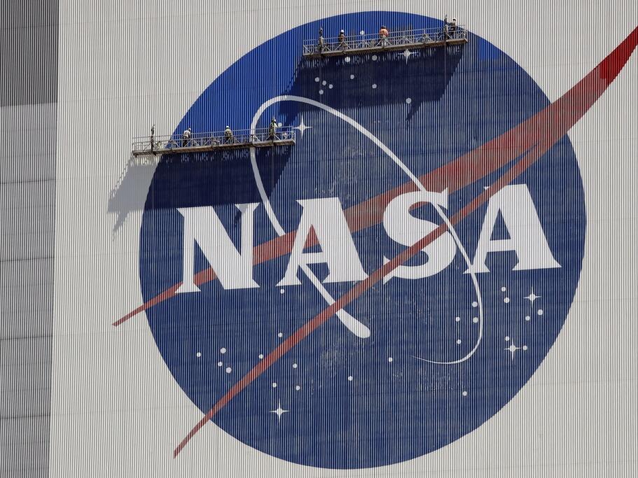 Workers on scaffolding repaint the NASA logo near the top of the Vehicle Assembly Building in 2020 at the Kennedy Space Center in Cape Canaveral, Fla.