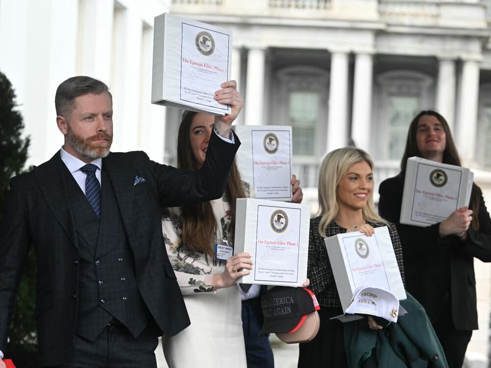 Several conservative commentators carry binders bearing the seal of the Justice Department and reading 
