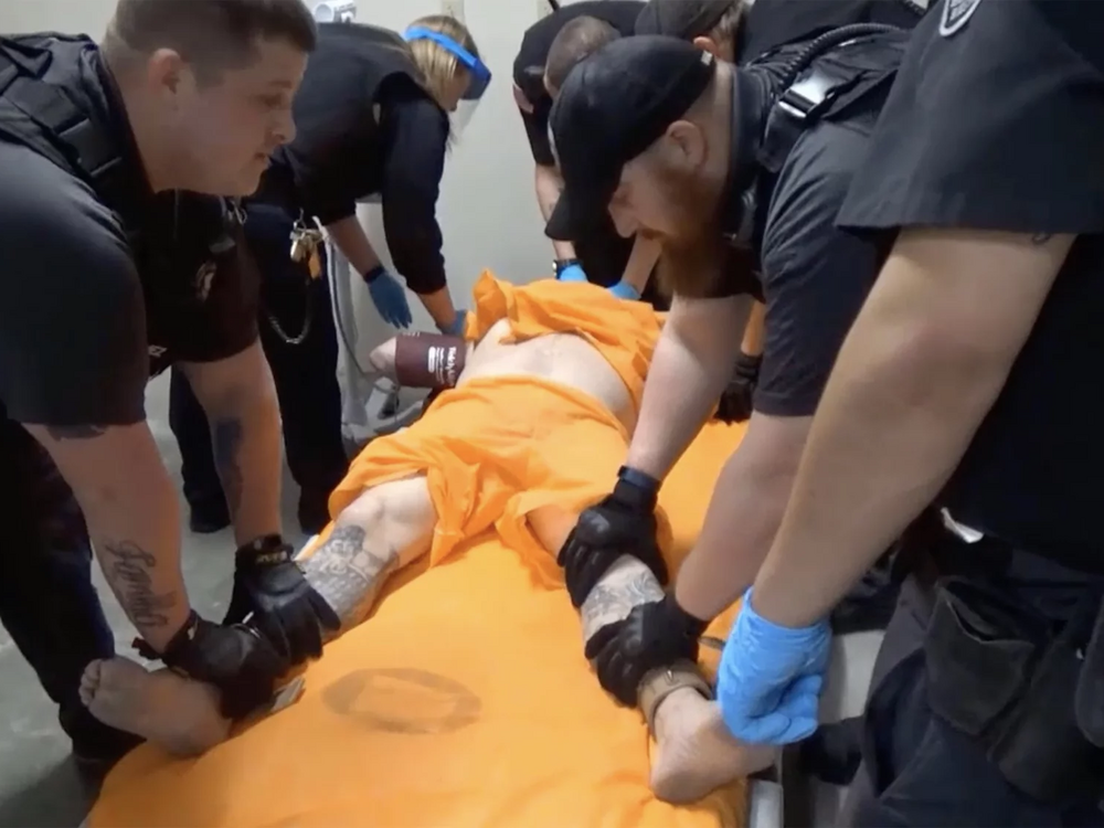 A screenshot from a video of officers at the U.S. penitentiary in Thomson, Ill., holding an incarcerated person in a four-point restraint.