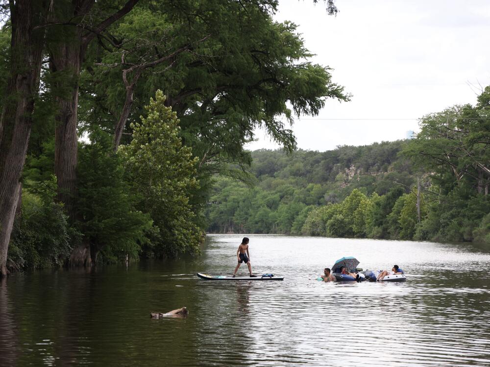 People swim in the Blanco River by a low water crossing on River Road across from 7A Ranch in Wimberley, Texas, on July 9.