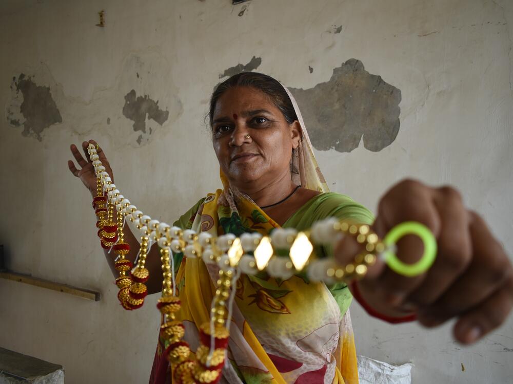Shobha Ben Bimabhai shows one of the decorative pieces she sells from her outdoor pushcart. She was able to stay home for a few days when temperatures soared above 100 degrees F without losing income as a result of her union's insurance program, offering payouts during extreme heat.