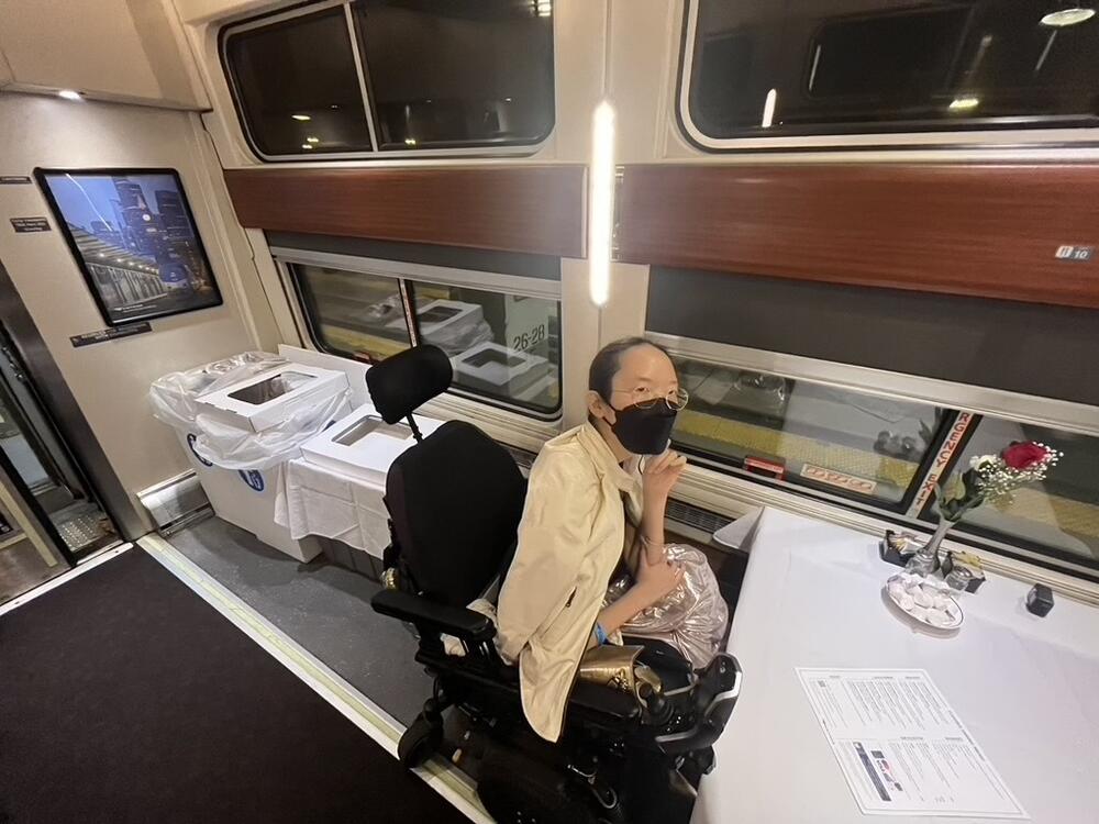 Aubrie Lee in her power wheelchair sitting at a table in the dining car of the Lake Shore Limited Amtrak train.
