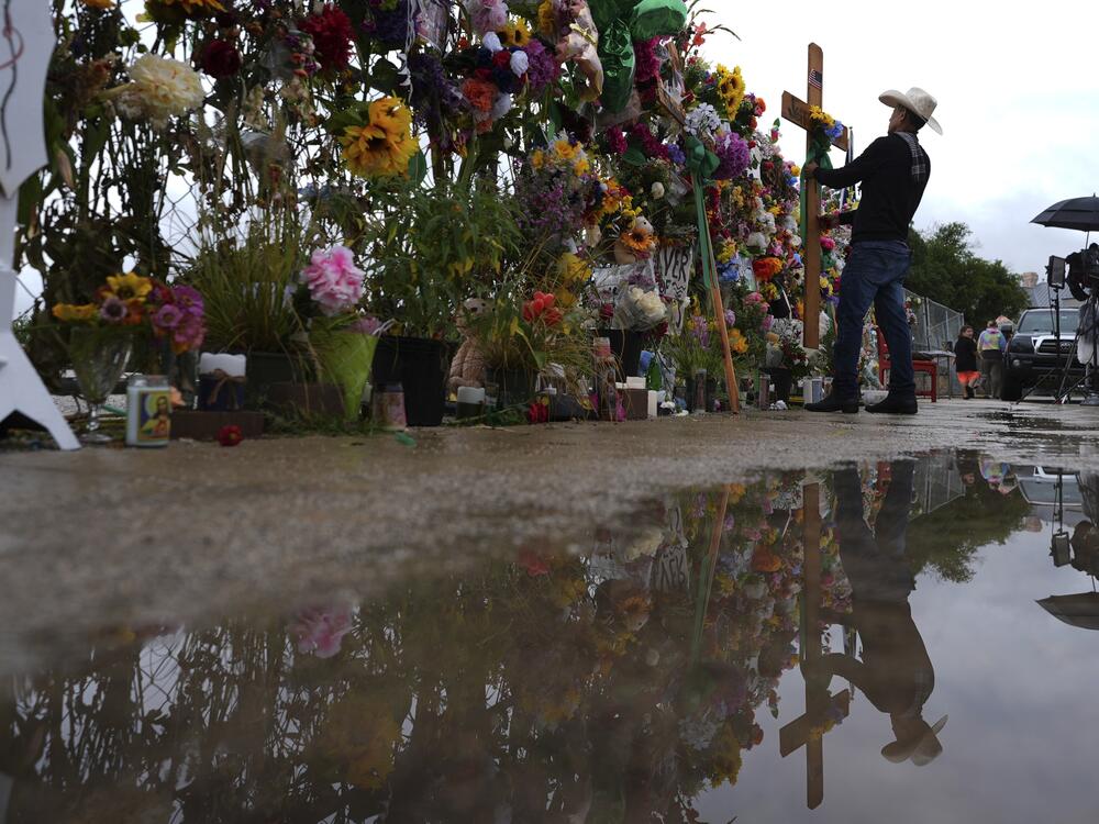 Roberto Marquez places a cross at a memorial wall for flood victims, Sunday, July 13, 2025, in Kerrville, Texas.