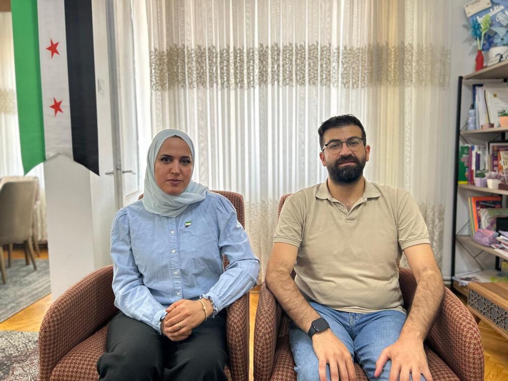 Bushra Ajaj and Hasan Ajam in their living room in Gaziantep, Turkey, with the new Syrian flag hanging behind them. The couple met in 2014 while protesting against the Assad regime in Syria.