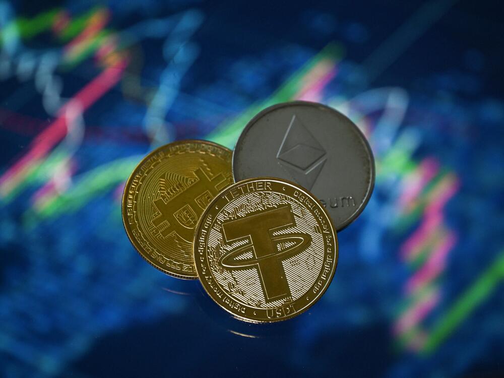An illustration picture shows a gold-plated souvenir Tether stablecoin, along with representations of crypto currencies Bitcoin and Ethereum coins.