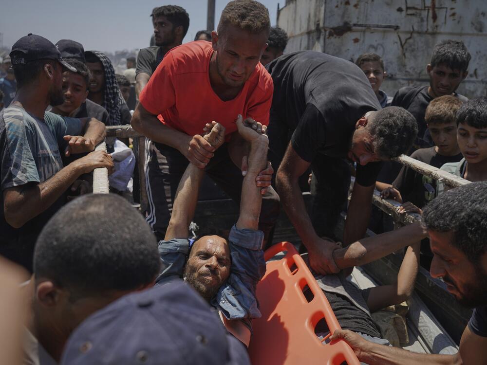 Injured Palestinians are transferred to an ambulance after being wounded while waiting for aid arriving from the northern Gaza Strip, in Gaza City, Tuesday.