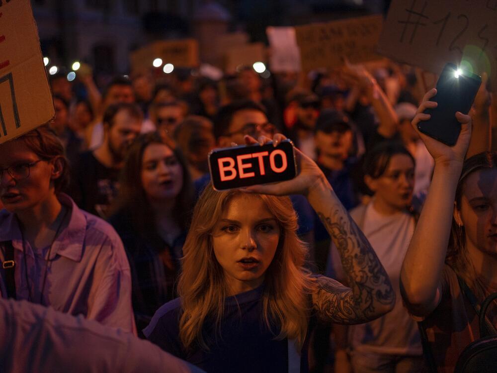 A woman holds a phone with a sign reads 