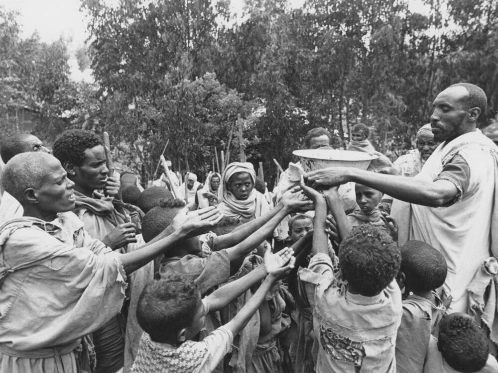 Food is distributed to children at a relief camp in Ethiopia during the famine in the 1985. The famine in Ethiopia in the mid-1980s was the impetus for the establishment of FEWS NET, a U.S.-funded famine alert project.