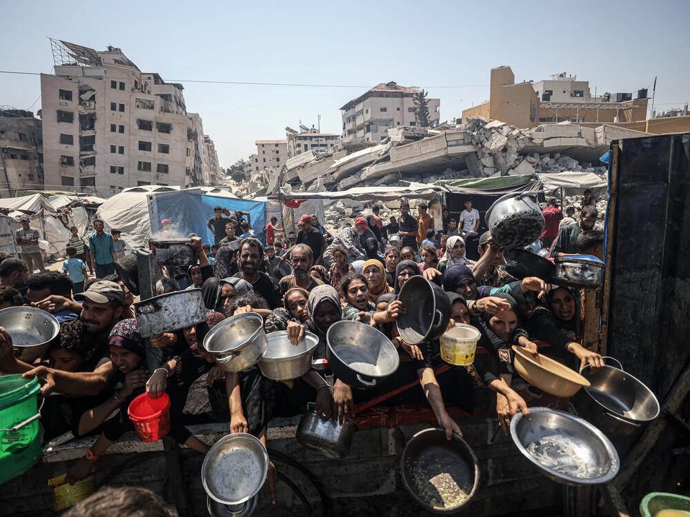 Palestinians in Gaza City hold out pans at a food distribution run by a charity. The World Food Programme said Monday that hunger in Gaza has reached 