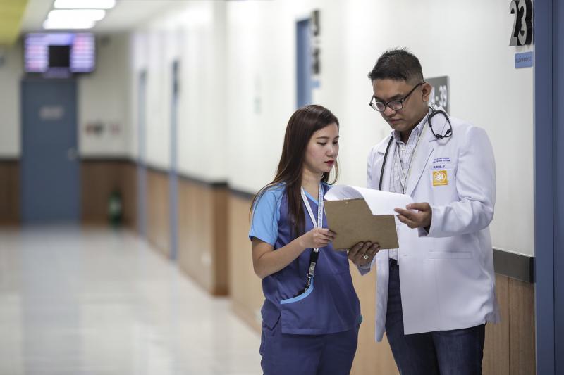 A doctor talks with an assistant in a hospital corridor