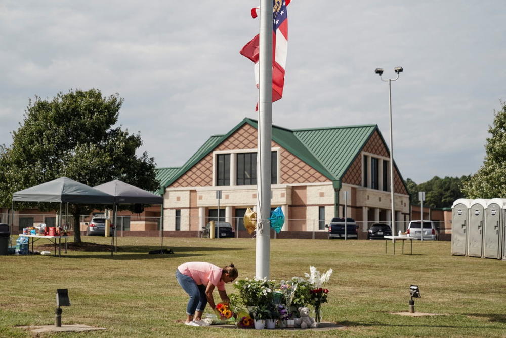 A woman lays flowers at the base of a flagpole turned into a makeshift memorial in front of Apalachee High School the day after a fatal shooting left four dead in Winder, Georgia, U.S. September 5, 2024. REUTERS/Elijah Nouvelage