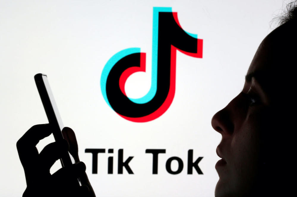 A person holds a smartphone as Tik Tok logo is displayed behind in this picture illustration taken November 7, 2019. Picture taken November 7, 2019. REUTERS/Dado Ruvic/Illustration