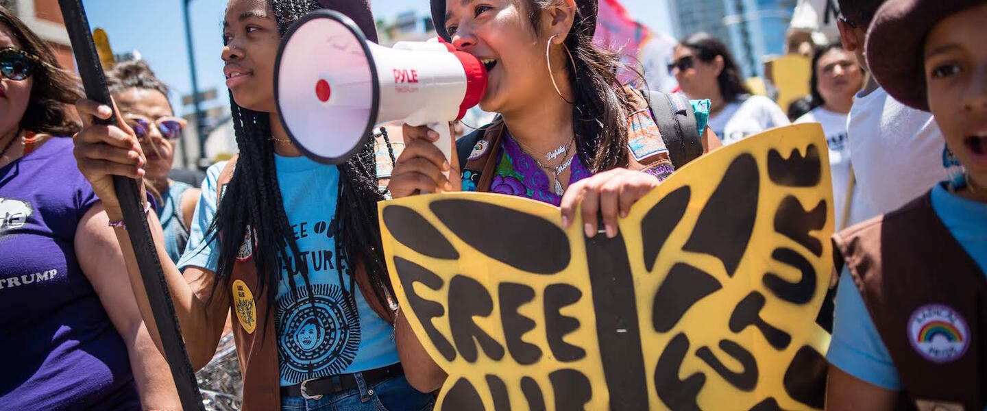 Members of the Radical Monarch troupe marching with signs.
