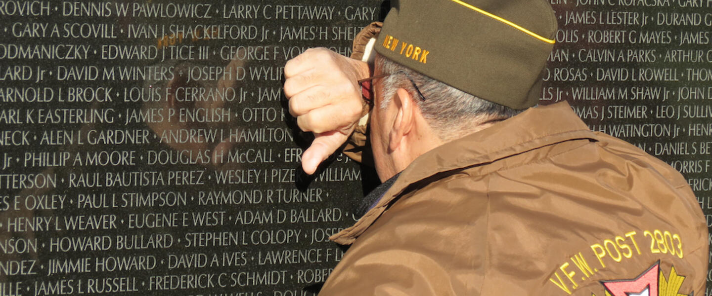 A man in a VFW jacket mourning.