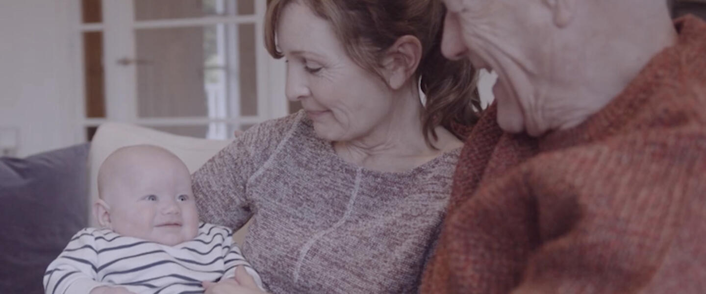 A couple hold their smiling grandchild.