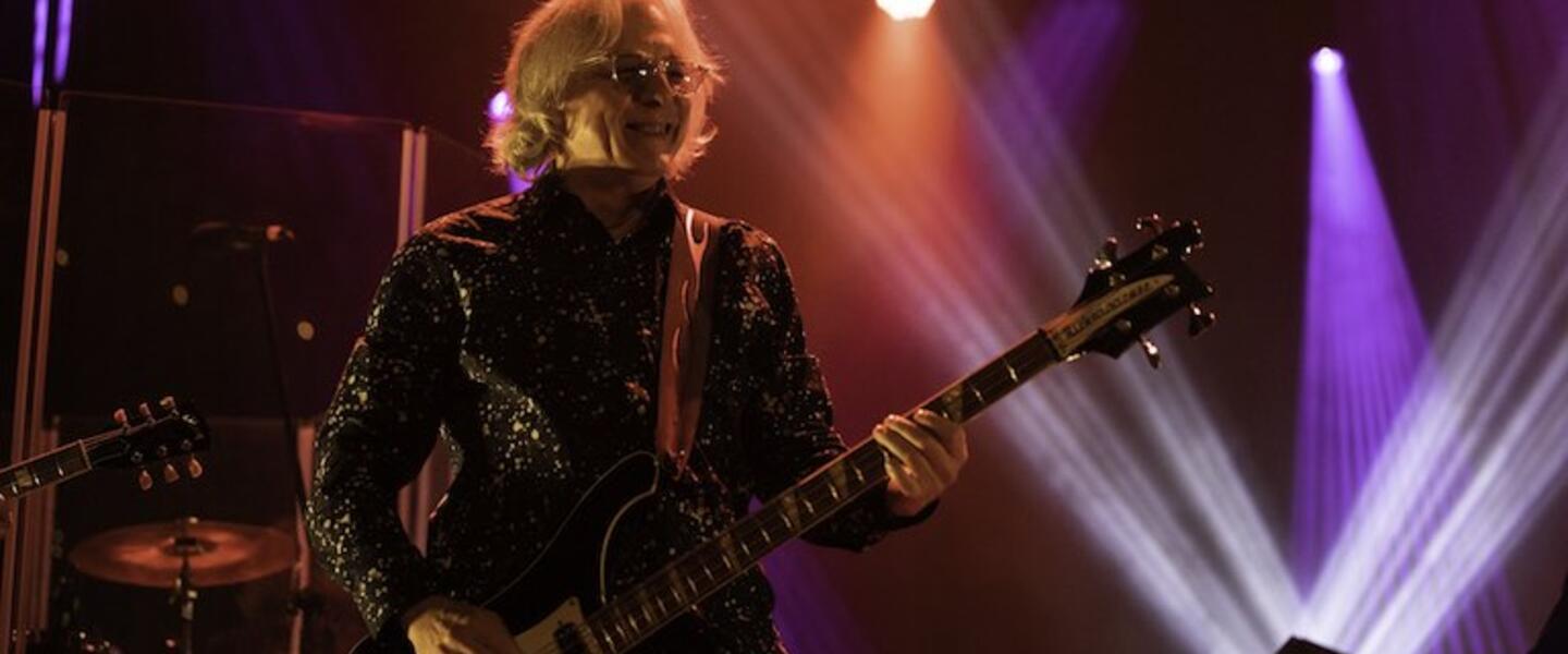 Mike Mills playing guitar on stage.