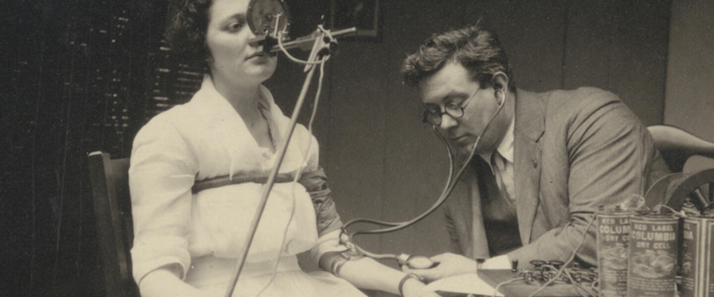 A man using a polygraph on a seated woman.