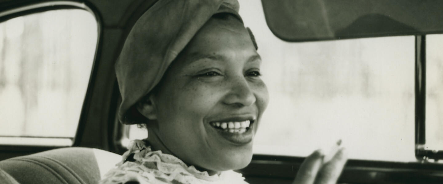 Zora Neale Hurston smoking a cigarette in a car.