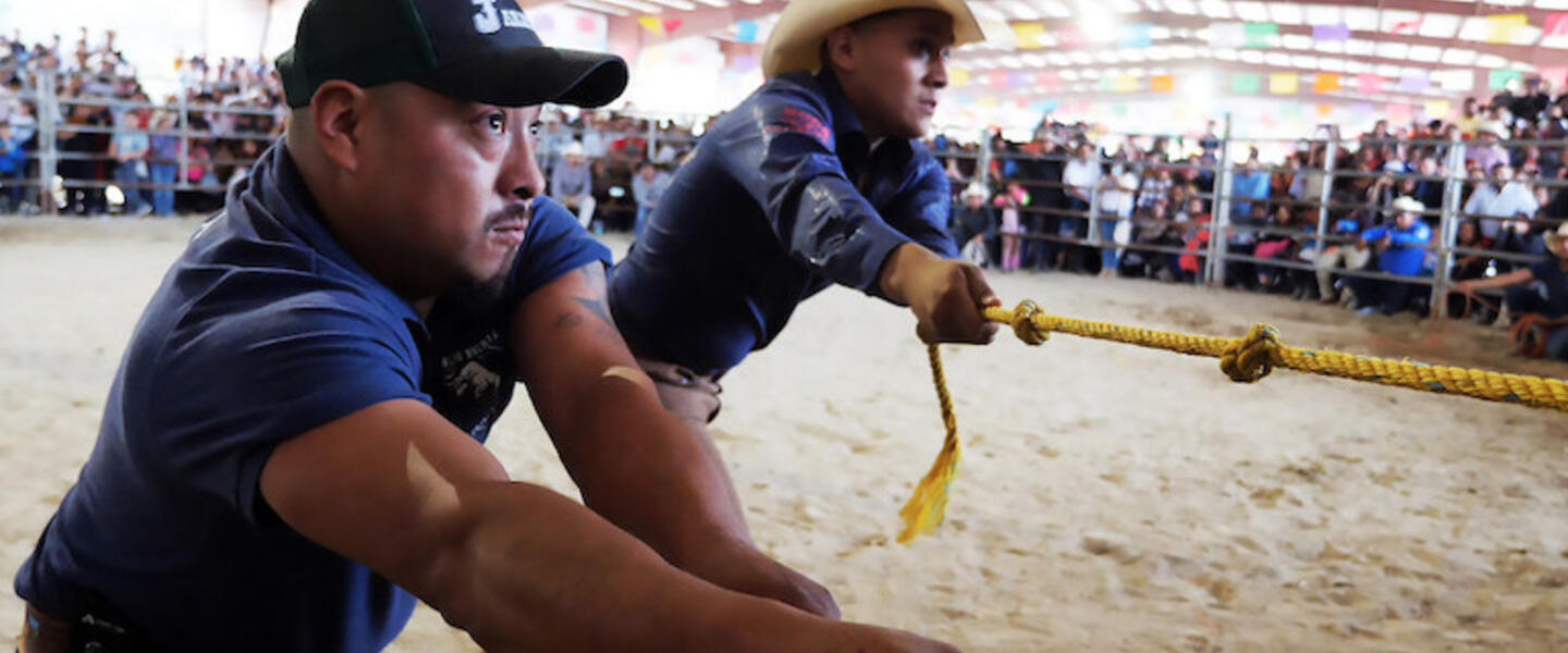 Two men pulling a rope at a rodeo.