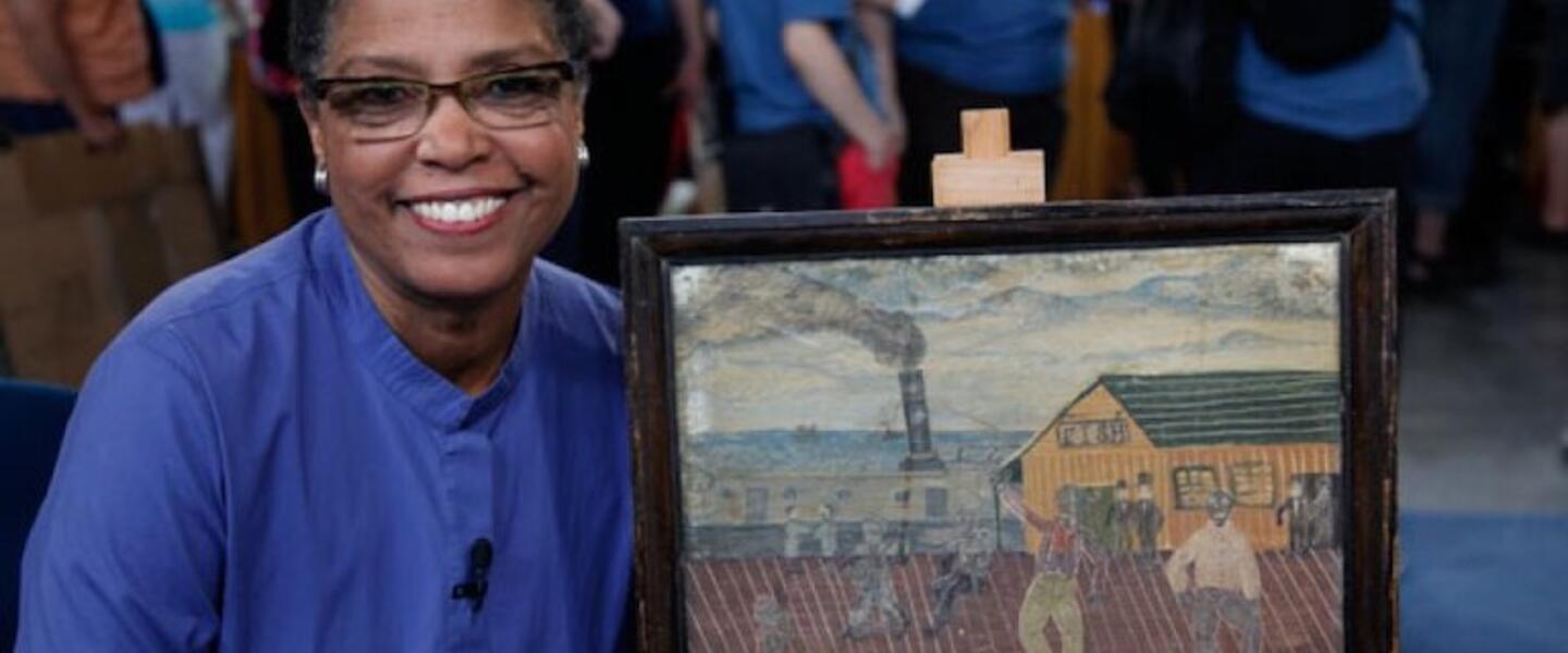 A woman smiling next to a painting.