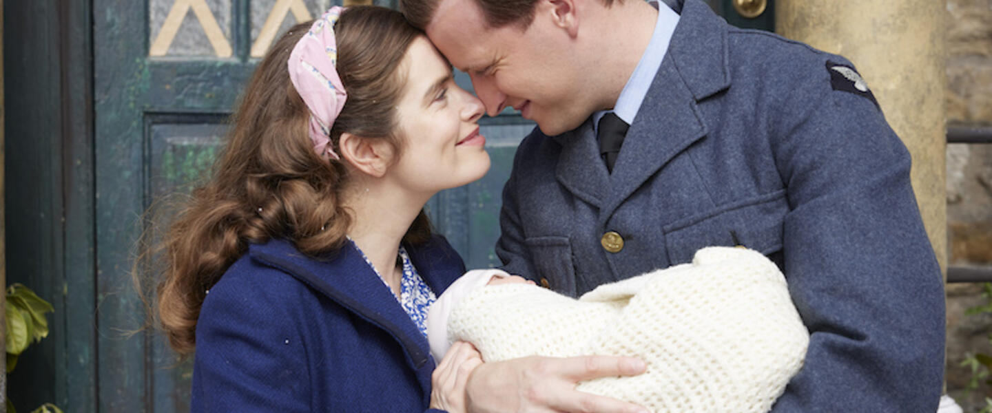 A couple holding a baby and looking lovingly at one another. From All Creatures Great and Small.