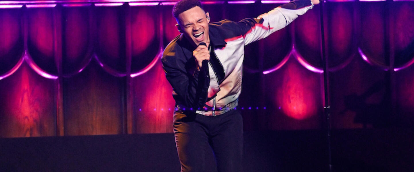 A man giving a passionate vocal perfomance on stage.