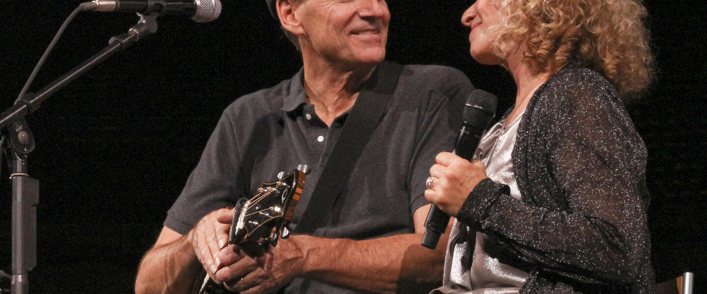Carole King and James Taylor together on stage.