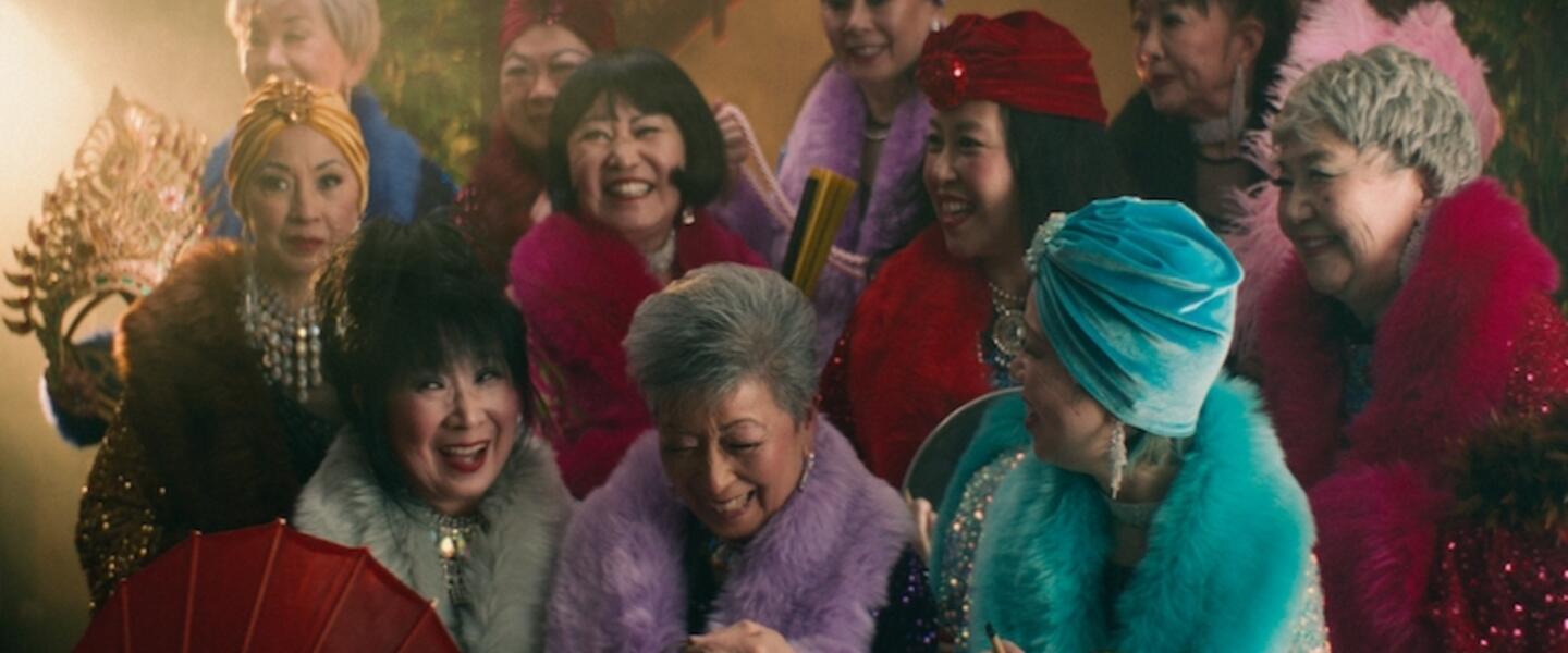 A group of smiling elderly ladies in fancy dress