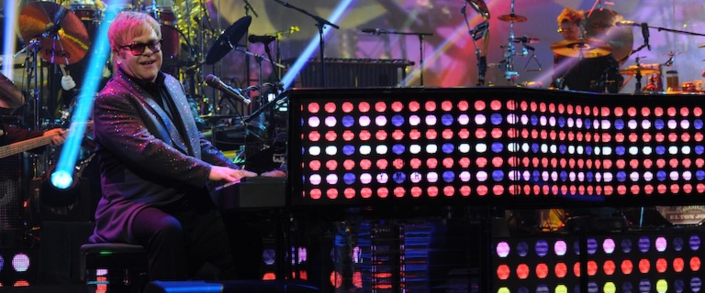 Elton John playing a piano wrapped in LED