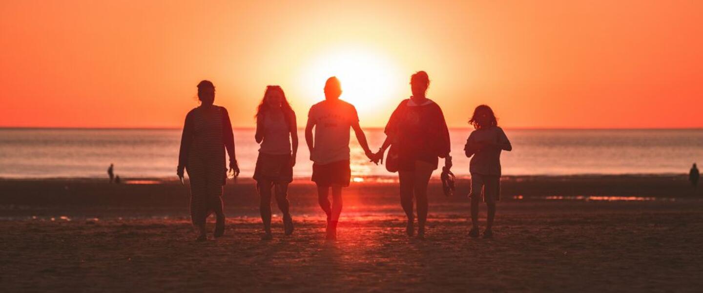 Silhouettes of a family of 5 on the beach at sunset.