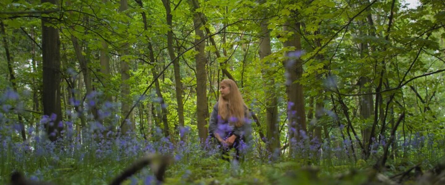 A woman standing in a forest.