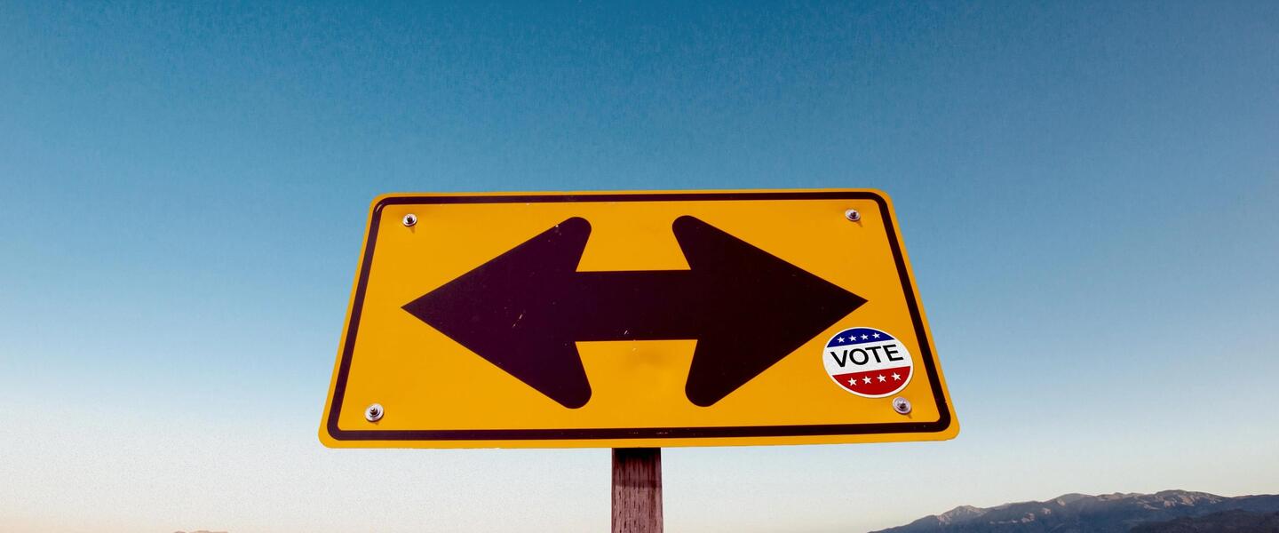 A road sign with a vote sticker on it.