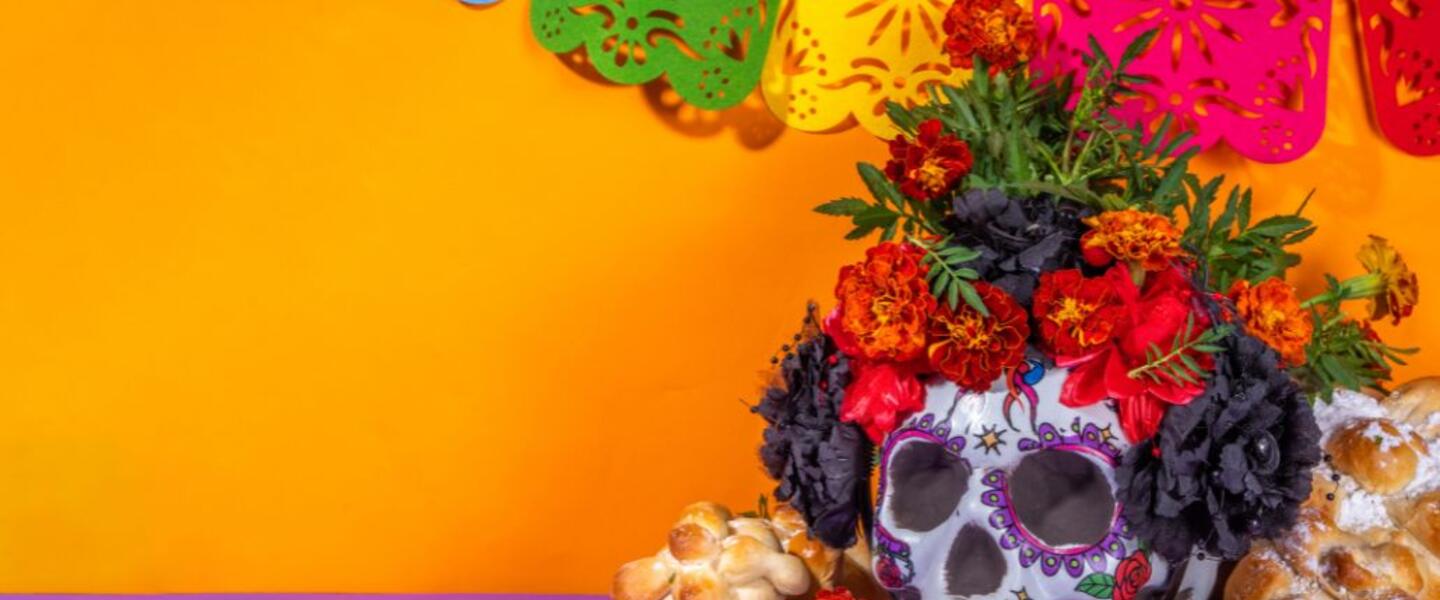 A skull sits prominently in front of an ofrenda, or Día de los Muertos offering table.