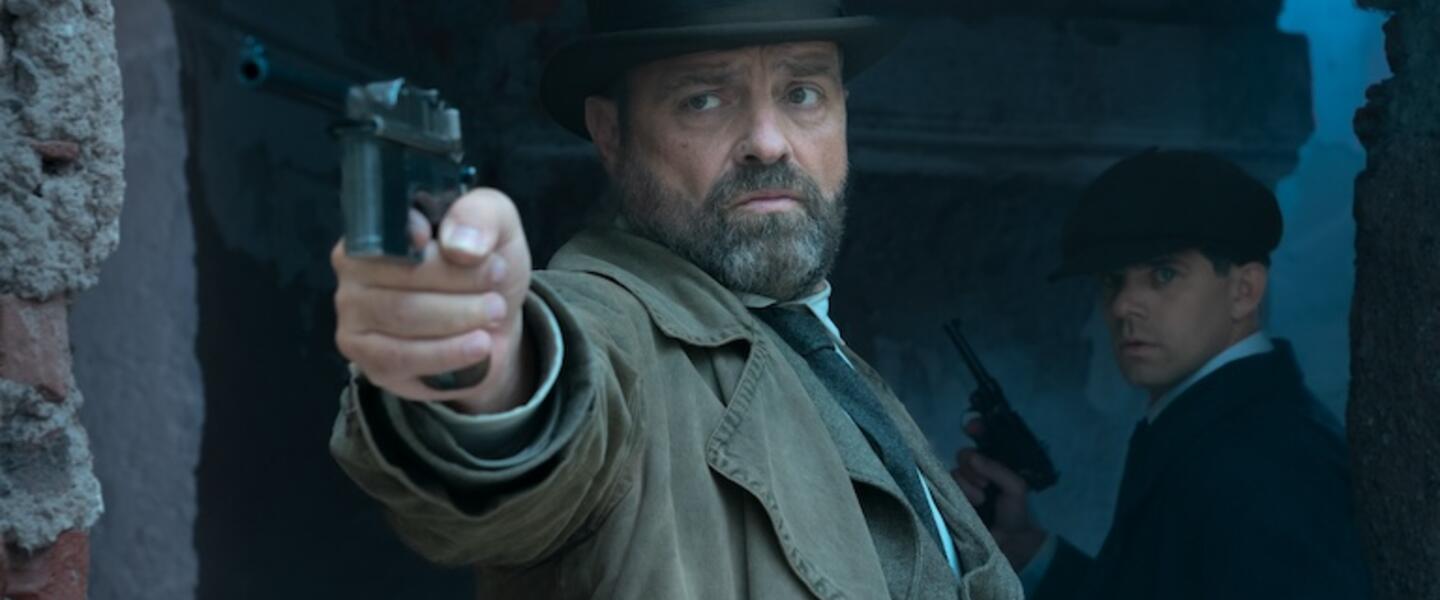A man standing in a corridor pointing a gun.