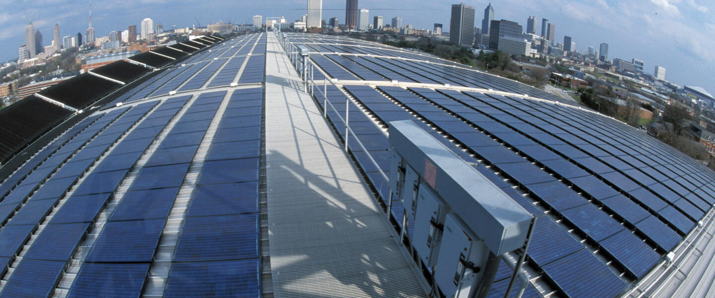 Solar panels are seen atop the Georgia Tech Aquatic Center with the Atlanta skyline in the distance.