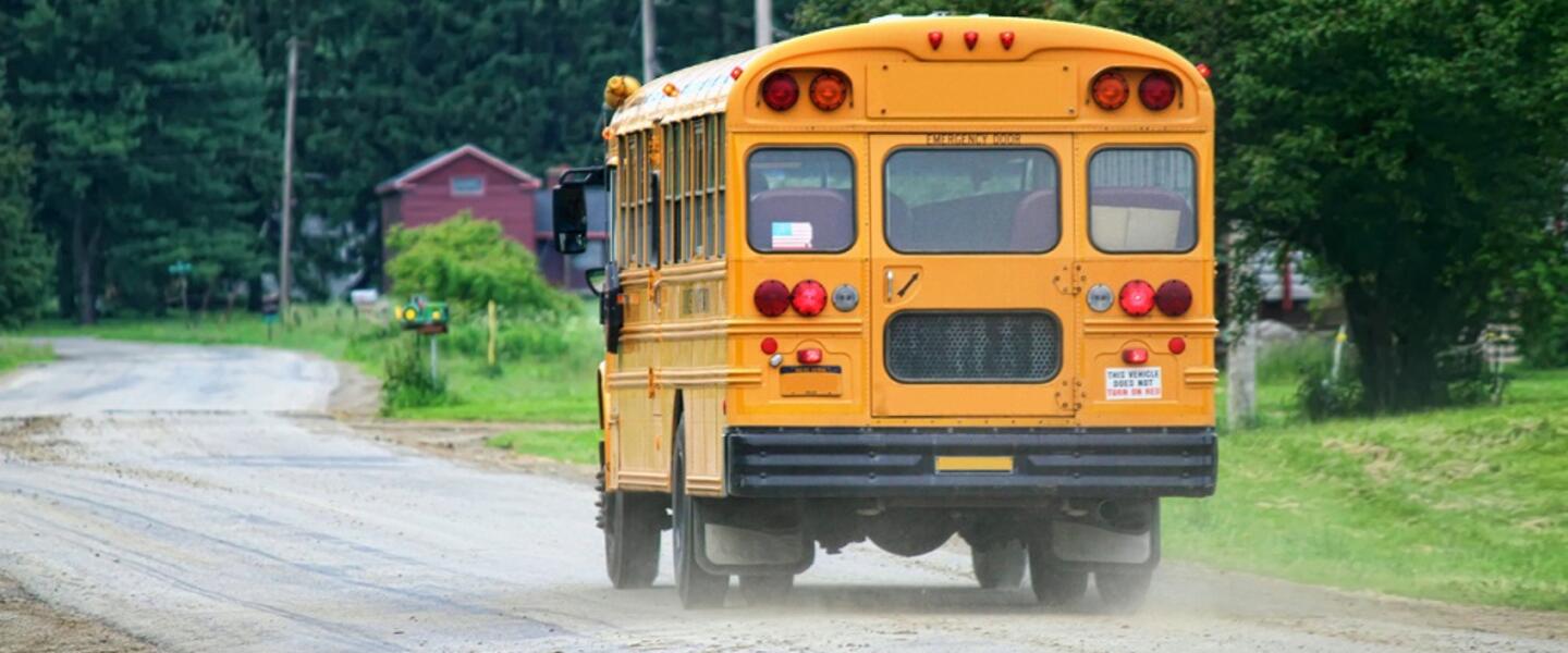 A school bus rolls down a rural road.