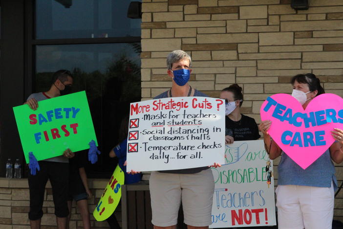 People hold signs advocating for mandatory masks and teacher safety when schools reopen in Cherokee County