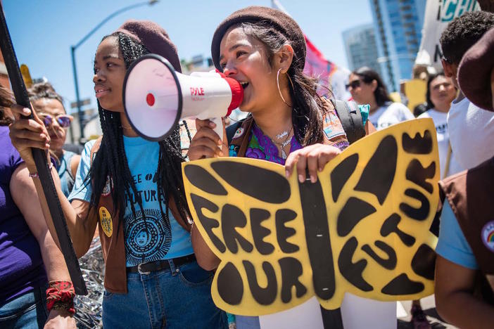 Members of the Radical Monarch troupe marching with signs.