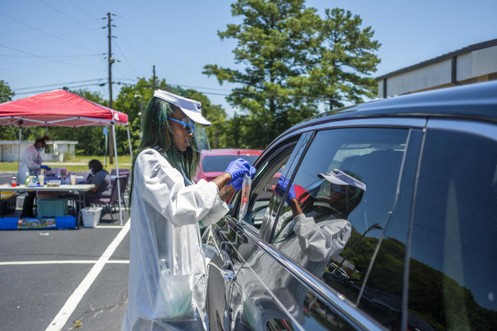 A Healthcare worker closes a plastic bag containing a coronavirus test kit