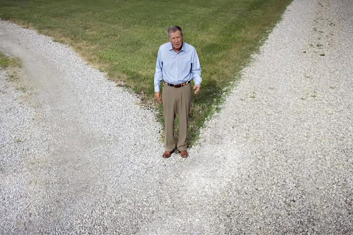John Kasich stands in a field as he address the Democratic National Convention in a pre-recorded video. 