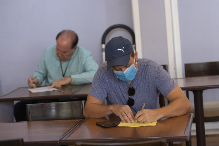 Elliott Zaagman from Michigan, front, votes on Super Tuesday for U.S. Democrats Abroad multi-location global primary, at Foreign Correspondents' Club of Thailand in Bangkok, Tuesday, March 3, 2020. 