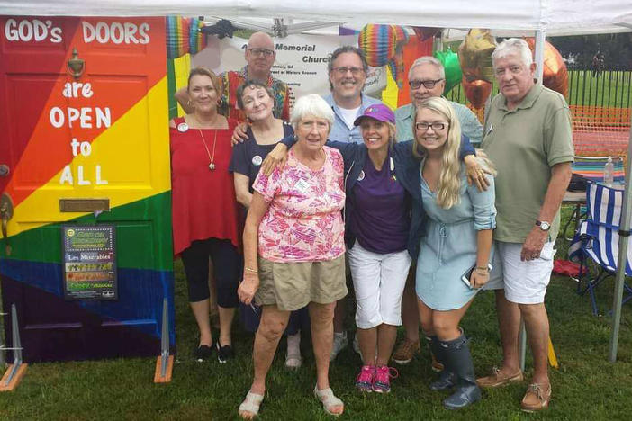 Members of Savannah's Asbury Memorial Church pose with a rainbow-painted door that says "God's Doors are Open to All"