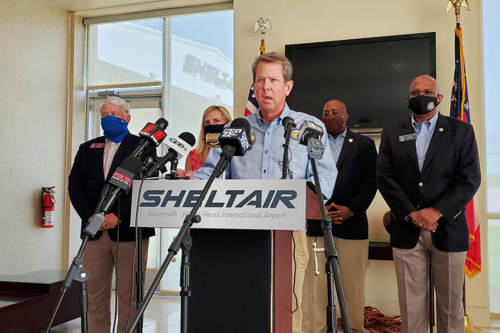 Brian Kemp speaks in Savannah, flanked by local officials.